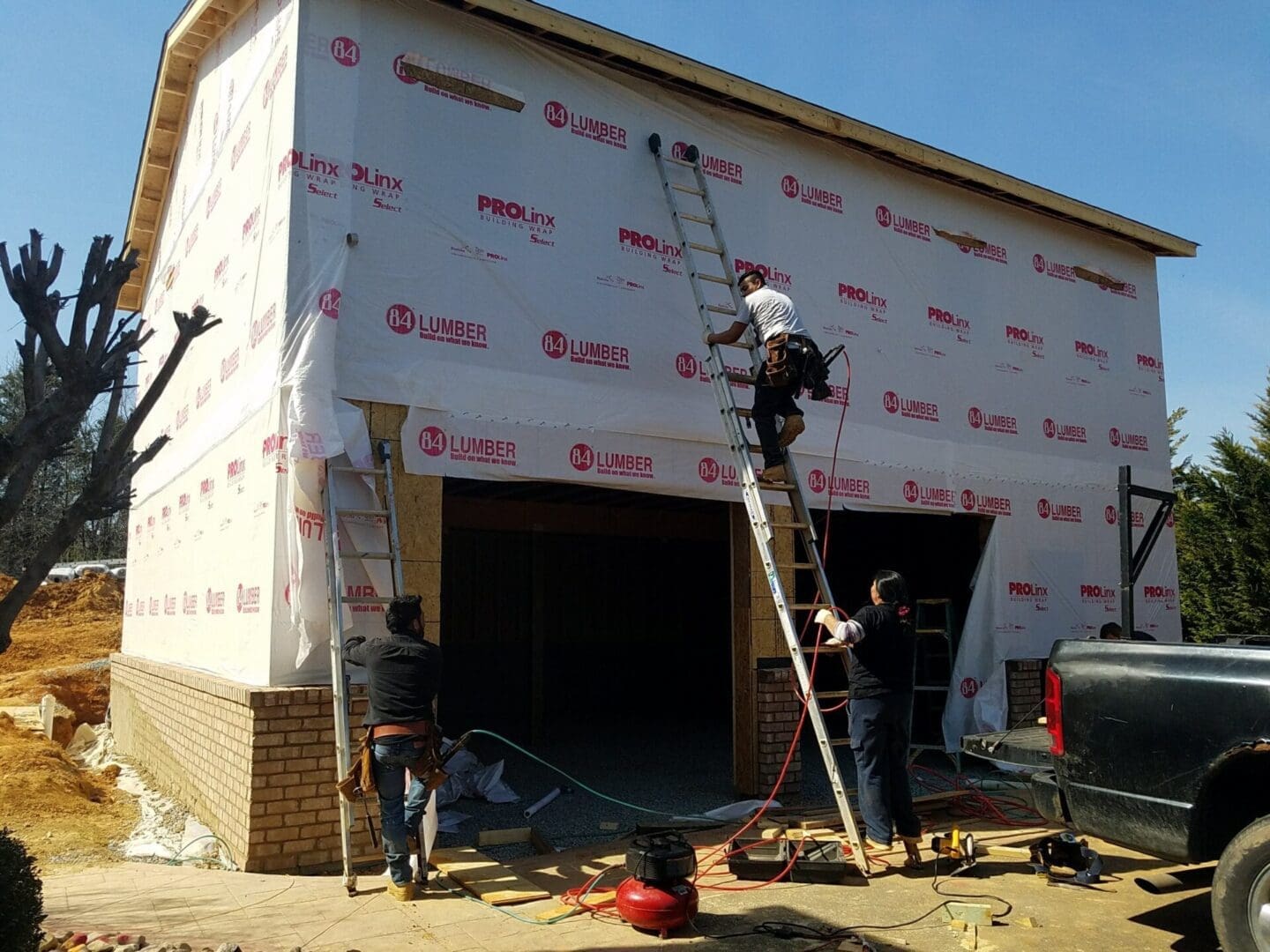 Workers installing siding on a building.